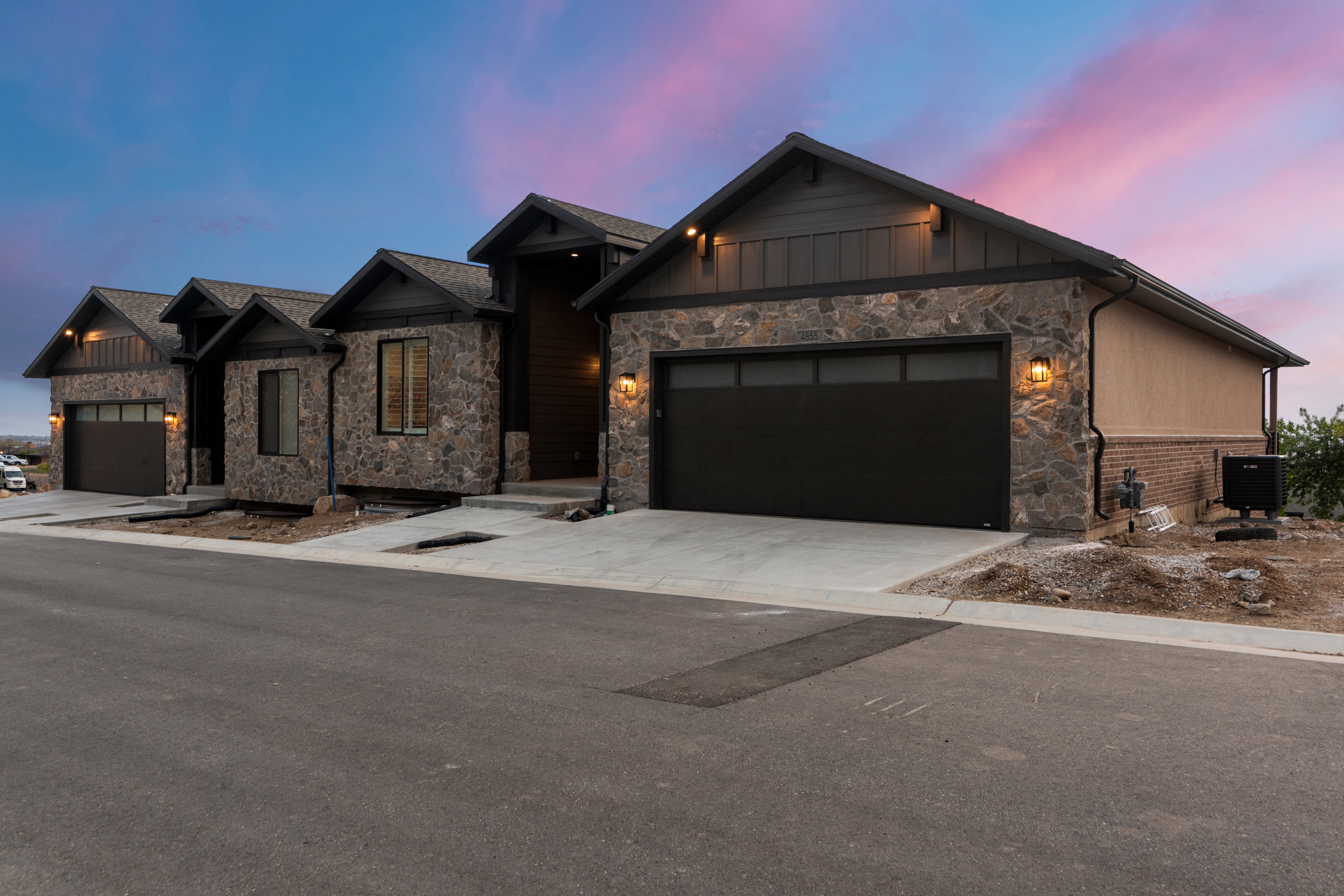 View of front of property with an attached garage, stone siding, concrete driveway, and board and batten siding