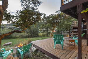 Wooden deck featuring stairway, an outdoor fire pit, and a fenced backyard
