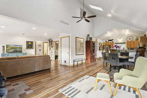 Living room featuring a skylight, light wood-style flooring, high vaulted ceiling, and recessed lighting