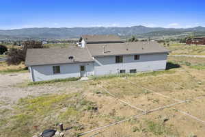 Back of house with a mountain view and a shingled roof