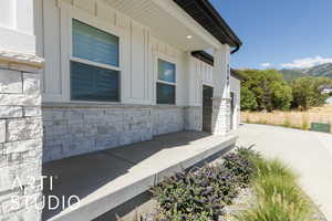 View of side of home featuring stone siding, driveway, board and batten siding, and a mountain view