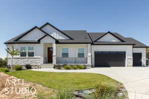 View of front of property featuring board and batten siding, stone siding, a front yard, and an attached garage