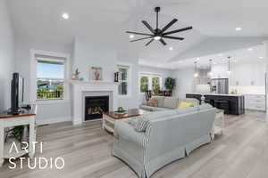 Living area with lofted ceiling, light wood finished floors, a glass covered fireplace, recessed lighting, and ceiling fan