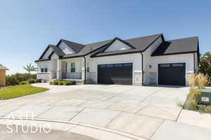 Modern inspired farmhouse with a garage, board and batten siding, concrete driveway, and stone siding