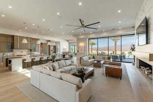 Living room with light wood finished floors, a fireplace, ceiling fan, and recessed lighting