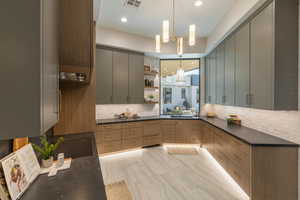 Kitchen featuring dark countertops, tasteful backsplash, open shelves, hanging light fixtures, and recessed lighting