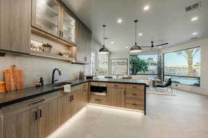 Kitchen featuring a peninsula, dark countertops, backsplash, decorative light fixtures, and open shelves