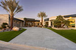View of front of home with curved driveway, a front yard, and an attached garage