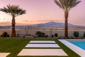 View of grassy yard with a water and mountain view, an outdoor pool, and a patio area