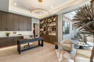 Office space featuring light wood-type flooring, a tray ceiling, and recessed lighting