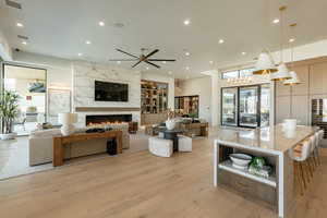 Living room with a fireplace, light wood-style flooring, ceiling fan, and recessed lighting