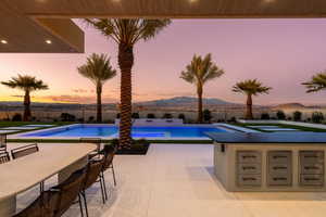 Pool at dusk with a hot tub, a patio area, a mountain view, and a fenced backyard