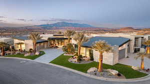 View of front of house featuring an attached garage, a mountain view, decorative driveway, a metal roof, and a standing seam roof