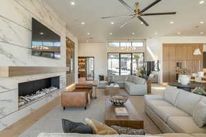 Living area with a high end fireplace, a chandelier, recessed lighting, and light wood-style floors
