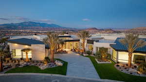 Contemporary home featuring a mountain view, curved driveway, stucco siding, a lawn, and a standing seam roof