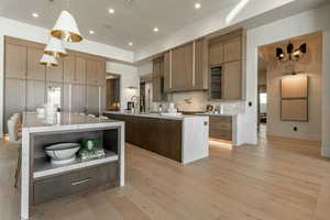 Kitchen with a spacious island, open shelves, modern cabinets, tasteful backsplash, and light countertops