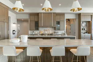 Kitchen with a large island, modern cabinets, recessed lighting, decorative backsplash, and hanging light fixtures