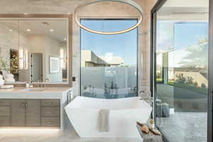 Bathroom featuring vanity, a freestanding bath, marble tiled flooring, and recessed lighting