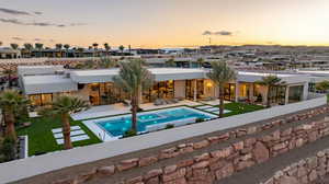 Back of house at dusk featuring a patio, stucco siding, and a pool with connected hot tub