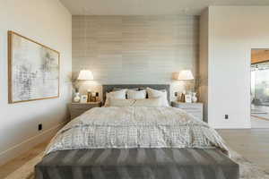 Bedroom with tile walls, wood finished floors, and an accent wall