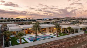 Back of house at dusk featuring a patio, an outdoor pool, and stucco siding