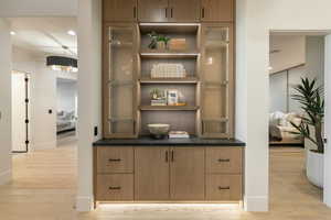 Bar with light wood-type flooring and recessed lighting