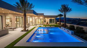 Pool at dusk featuring an outdoor pool, a patio, and a jacuzzi