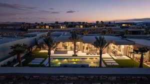 Pool at dusk featuring a patio area, a fenced backyard, and a pool with connected hot tub