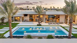 Back of house at dusk with stucco siding, a patio area, a putting area, and an outdoor hangout area