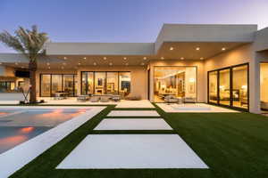 Back of house with an outdoor living space, a patio area, stucco siding, an outdoor pool, and a yard