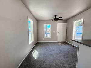 Unfurnished living room with healthy amount of natural light, carpet floors, a textured ceiling, and ceiling fan