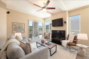 Living area featuring a glass covered fireplace, ceiling fan, and light carpet