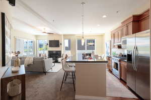 Kitchen with dark countertops, stainless steel appliances, a center island, a breakfast bar, and recessed lighting