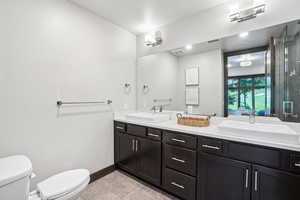 Full bath with double vanity, tile patterned floors, and a shower with door