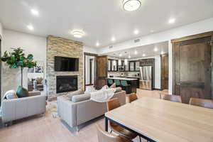 Living room with a stone fireplace, light wood-style flooring, and recessed lighting