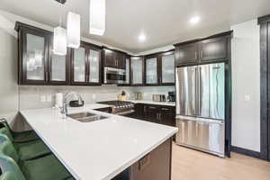 Kitchen featuring high end appliances, light countertops, dark brown cabinets, backsplash, and recessed lighting