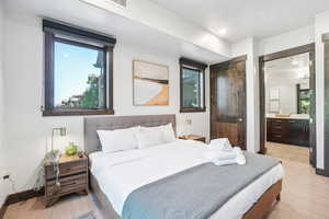 Bedroom featuring light wood-style flooring, recessed lighting, and connected bathroom