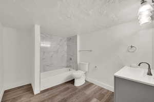 Full bathroom featuring vanity, light wood-style flooring, bathtub / shower combination, and a textured ceiling