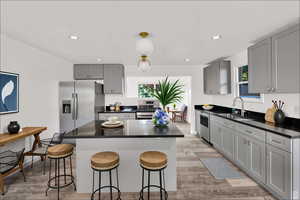 Kitchen with gray cabinets, light wood-type flooring, a kitchen bar, and recessed lighting