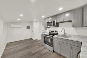 Kitchen with gray cabinets, appliances with stainless steel finishes, recessed lighting, light wood finished floors, and electric panel