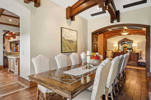 Dining space featuring beam ceiling, arched walkways, hardwood / wood-style flooring, and recessed lighting