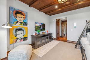 Living room featuring a wood ceiling with exposed beams, a barn door, and wood finished floors