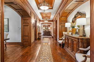 Hallway featuring arched walkways, ornamental molding, and dark wood-type flooring