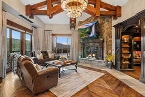 Living area with high vaulted ceiling, plenty of natural light, a fireplace, beam ceiling, and wood finished floors