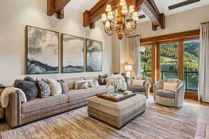 Living room with beam ceiling, a chandelier, and wood finished floors