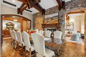 Dining space with arched walkways, beamed ceiling, a fireplace, and hardwood / wood-style flooring