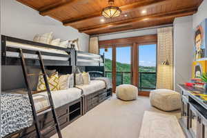 Carpeted bedroom with a wood ceiling with exposed beams