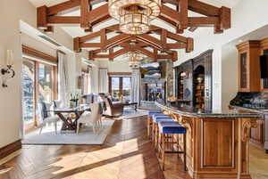 Bar area featuring dark stone counters, brown cabinets, glass insert cabinets, high vaulted ceiling, and decorative backsplash