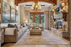 Living area with beamed ceiling, a fireplace, a chandelier, recessed lighting, and a high ceiling