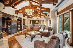 Living area with arched walkways, high vaulted ceiling, a chandelier, and beamed ceiling